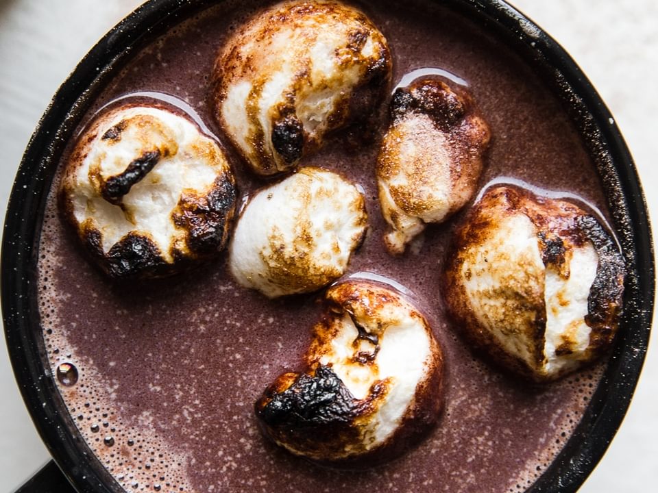 black mug of spiked hot chocolate topped with toasted marshmallows