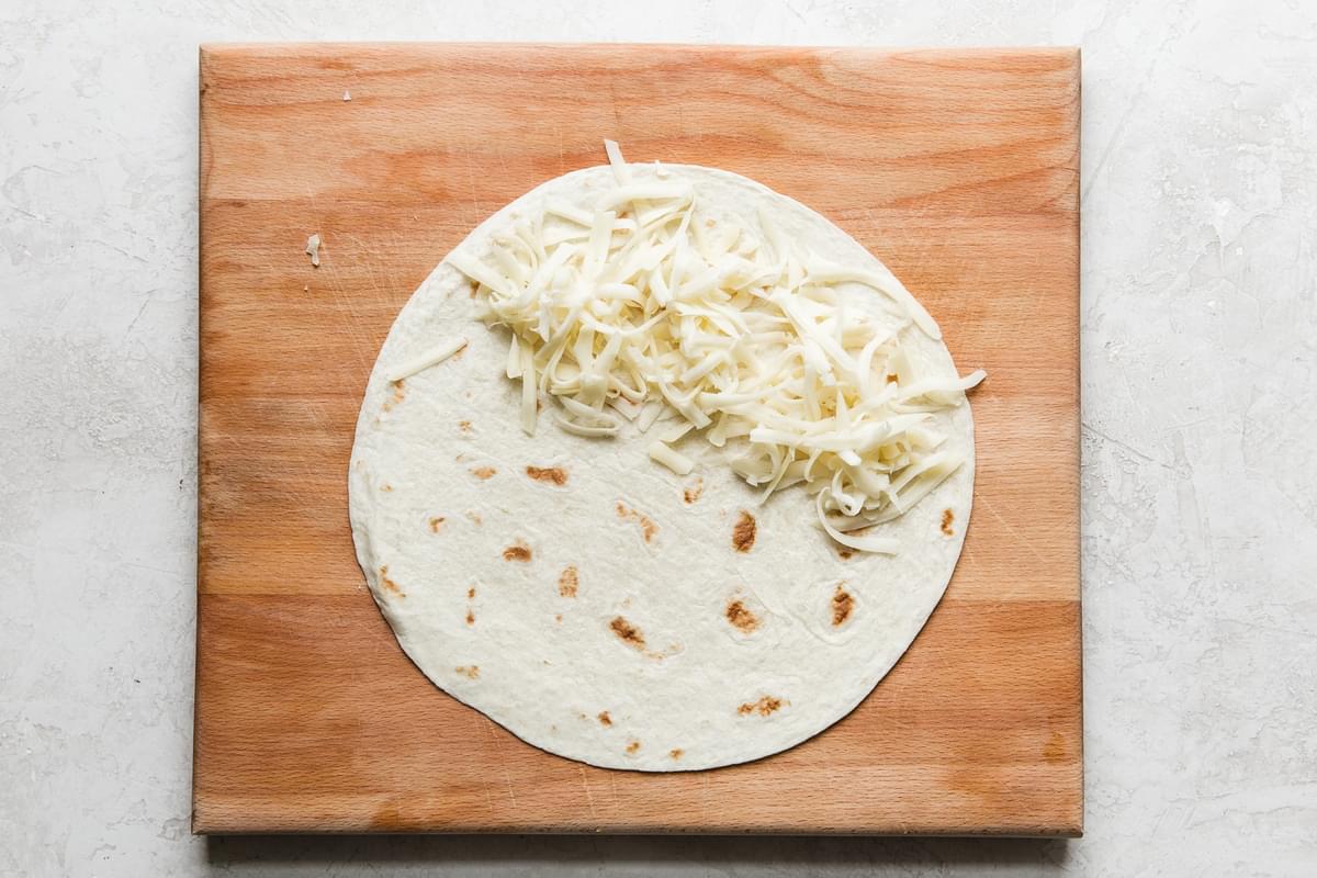Fontina cheese on a tortilla on a cutting board