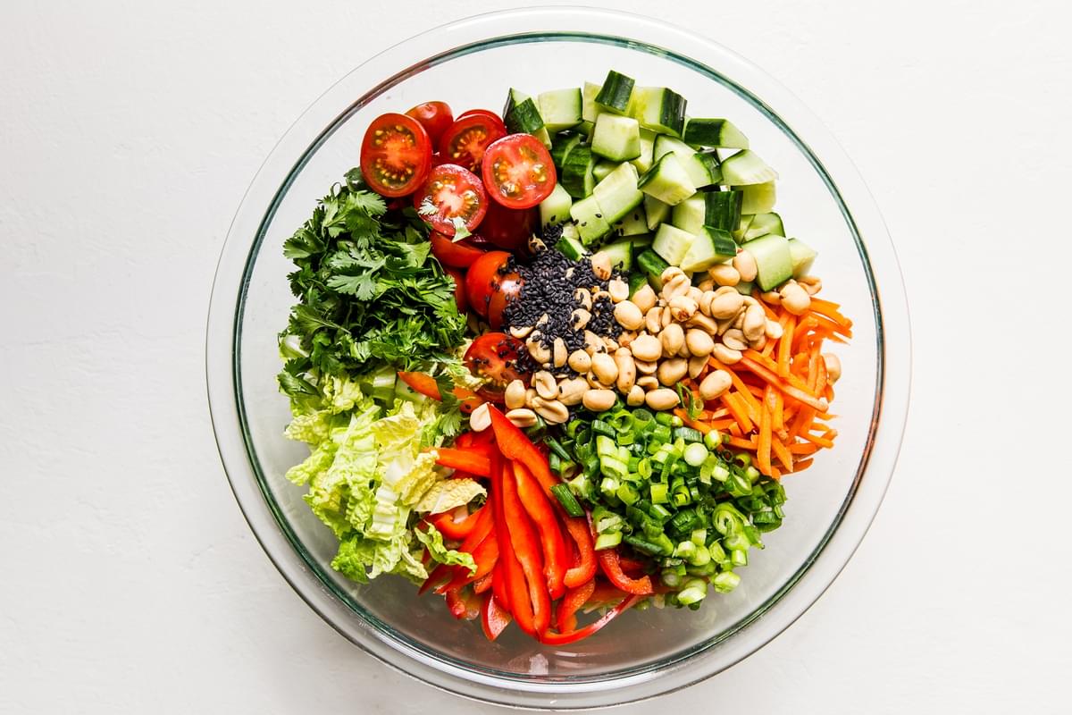 chopped ingredients for Asian chopped salad in a large glass bowl