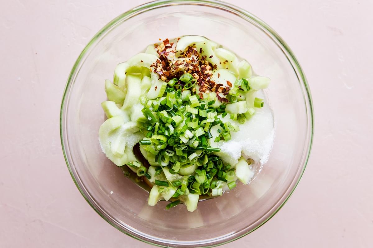 sugar, sliced cucumber, green onions, red pepper flakes, sesame oil and rice vinegar in a glass bowl