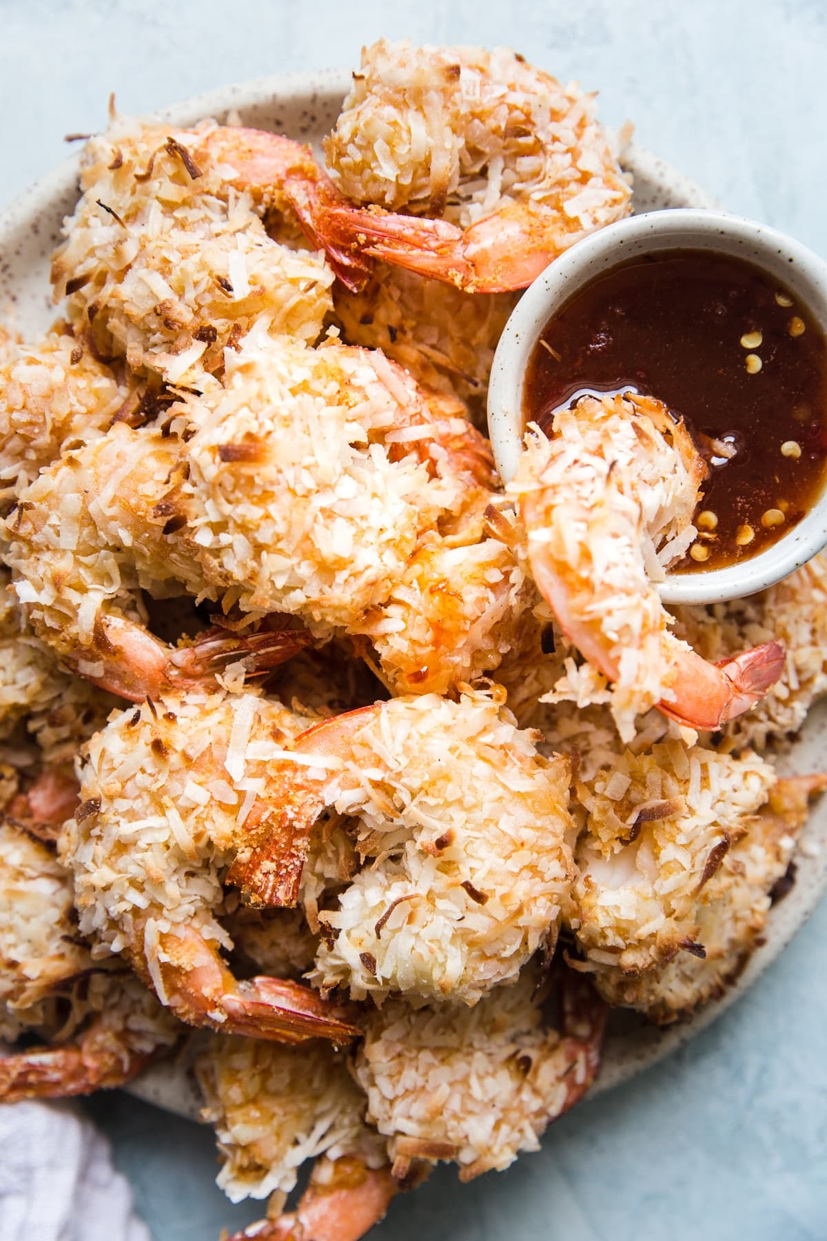 sweet coconut shrimp on a platter dipping into sweet and spicy sauce