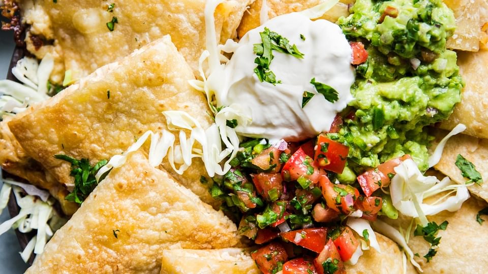 baked chicken quesadillas cut up and served with guacamole, fresh pico de gallo and sour cream