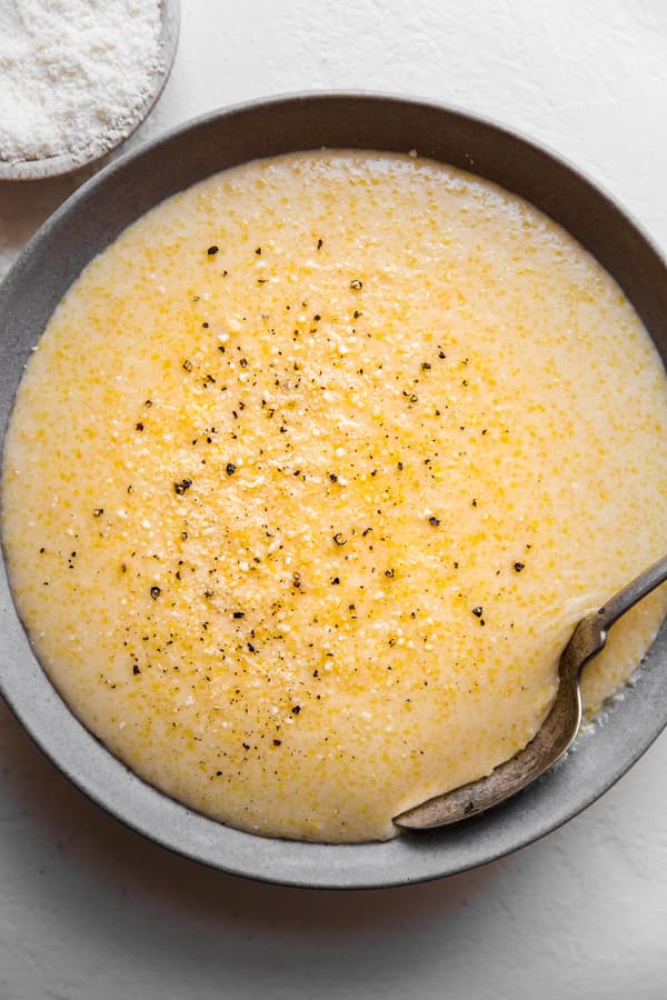 A bowl of creamy parmesan polenta in a bowl with a spoon