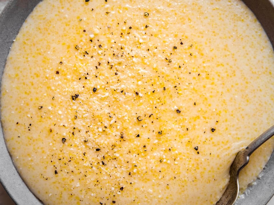 A bowl of creamy parmesan polenta in a bowl with a spoon