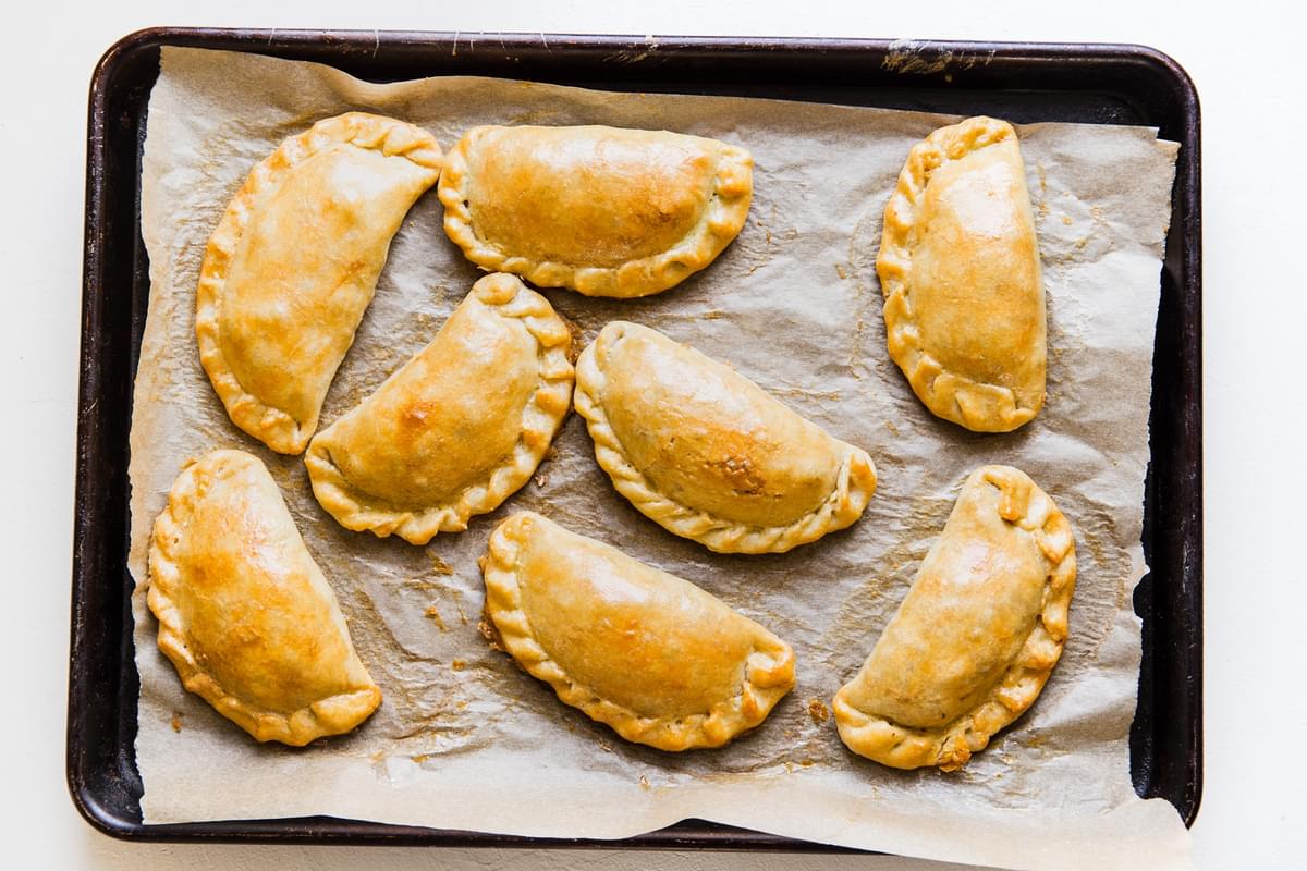 baked beef empanadas on a parchment lined baking sheet