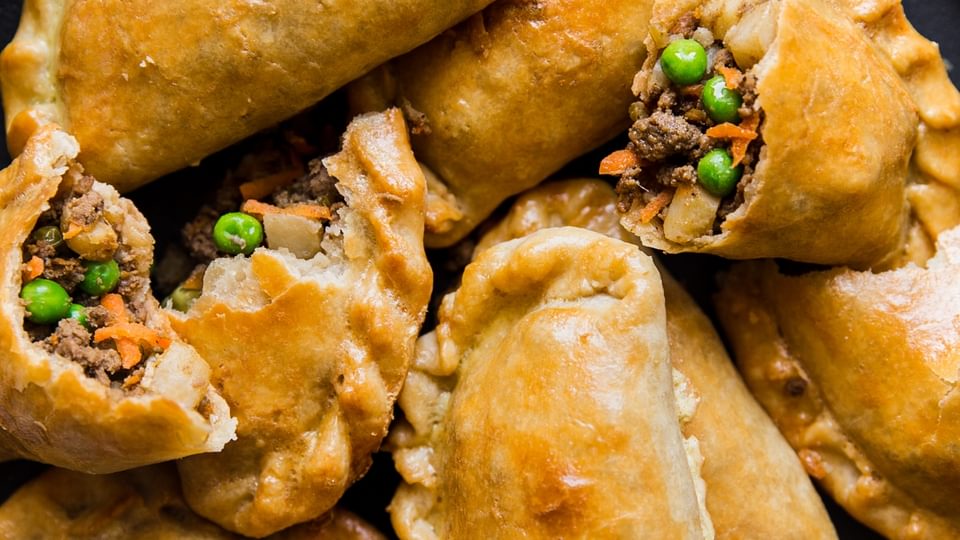 a stack of beef empanadas on a black plate