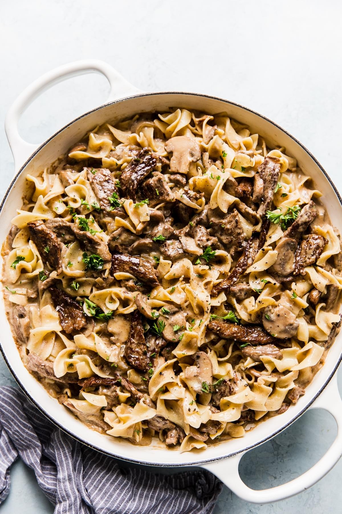 homemade beef stroganoff tossed with egg noodles and sprinkled with fresh parsley in a skillet