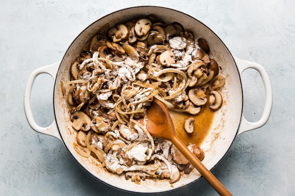 flour sprinkled on top of cooked onions, mushrooms and garlic in a skillet