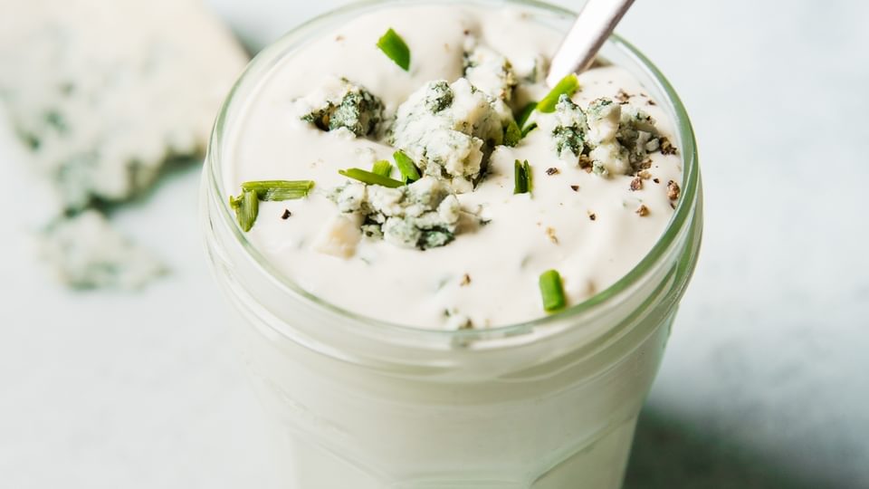 Homemade blue cheese dressing in a jar with a spoon.