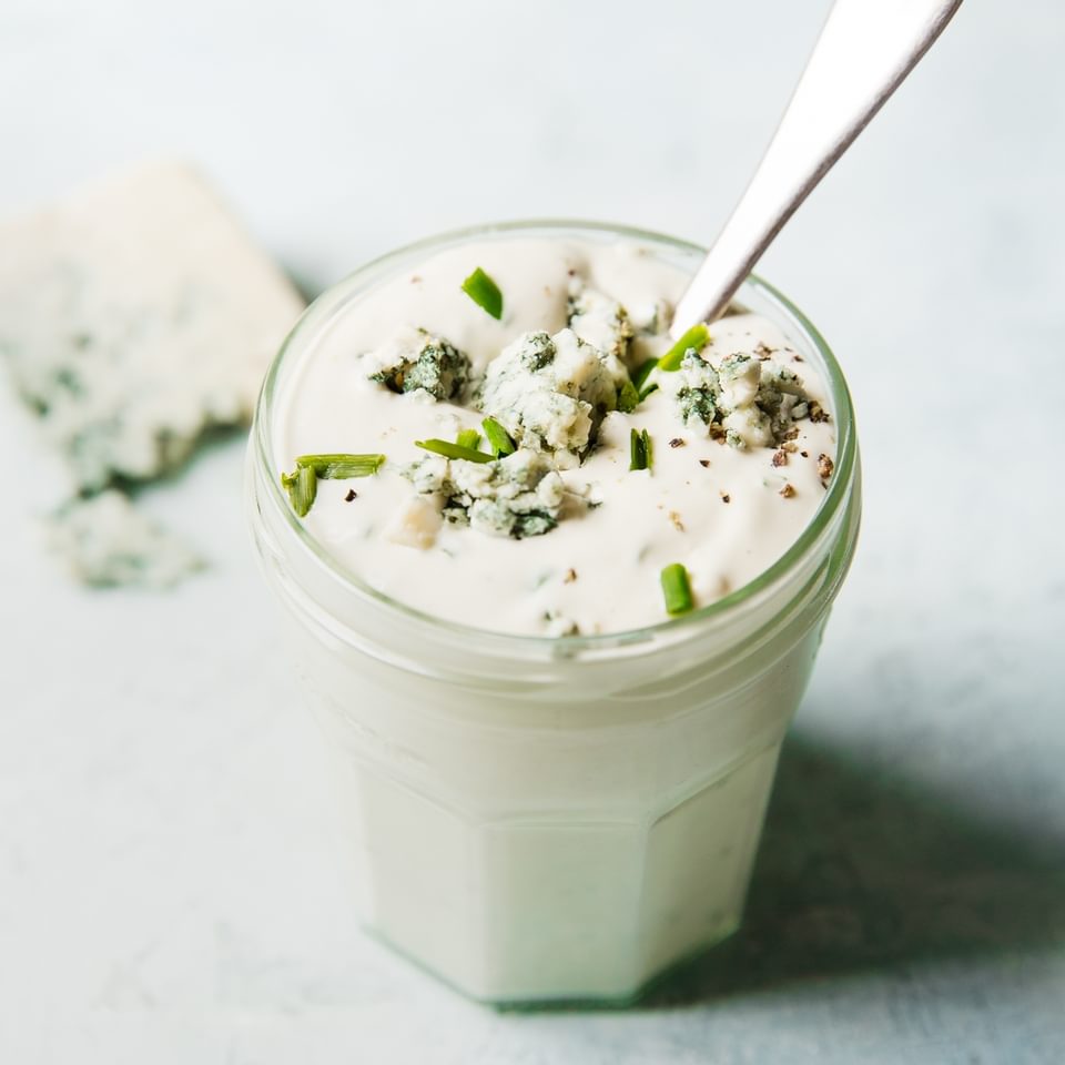 Homemade blue cheese dressing in a jar with a spoon.
