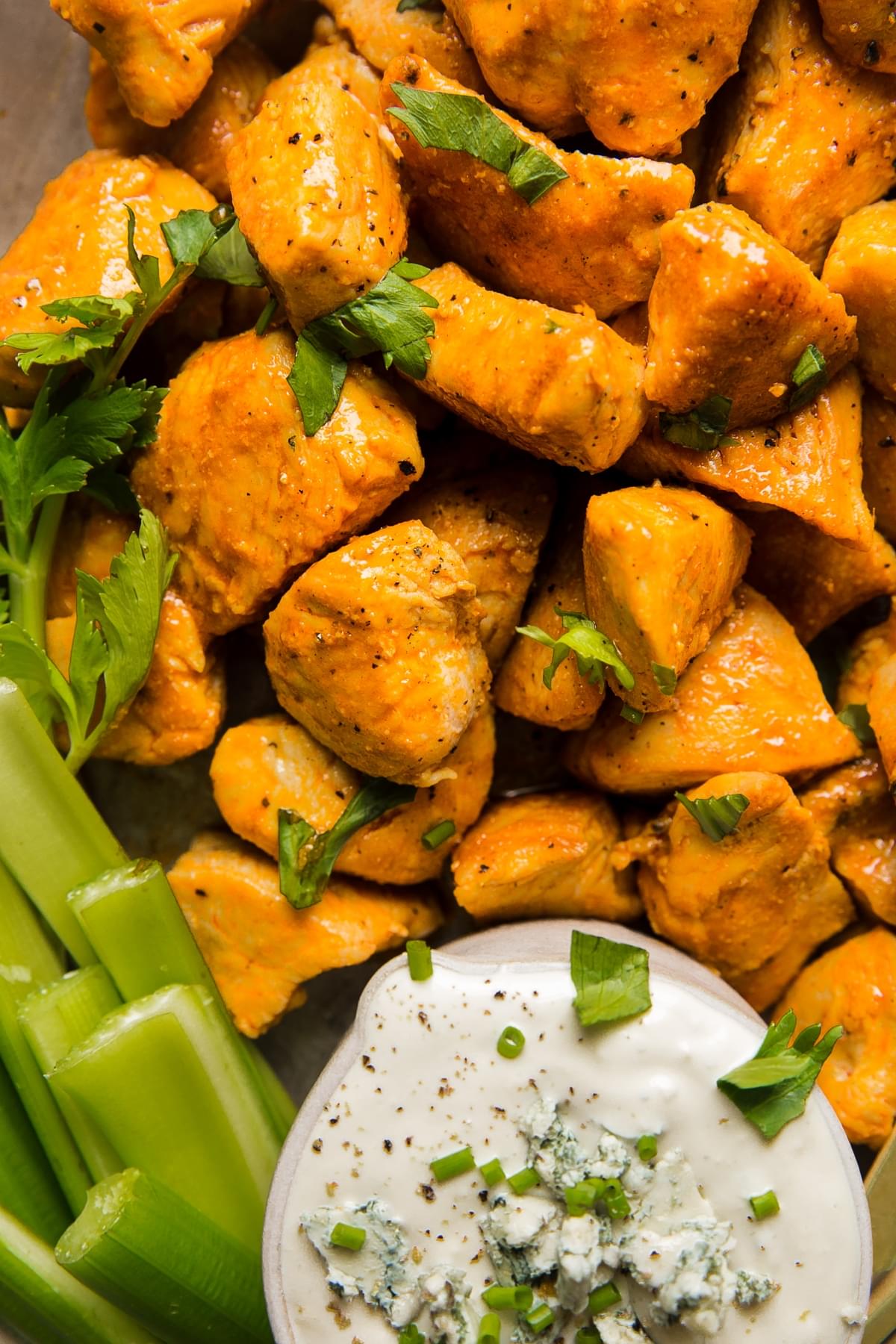 Buffalo chicken bites on a plate with blue cheese dressing and celery