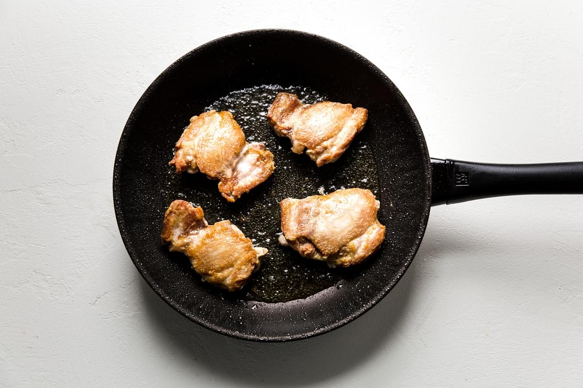Boneless Skinless Crispy Chicken Thighs in a cast iron pan