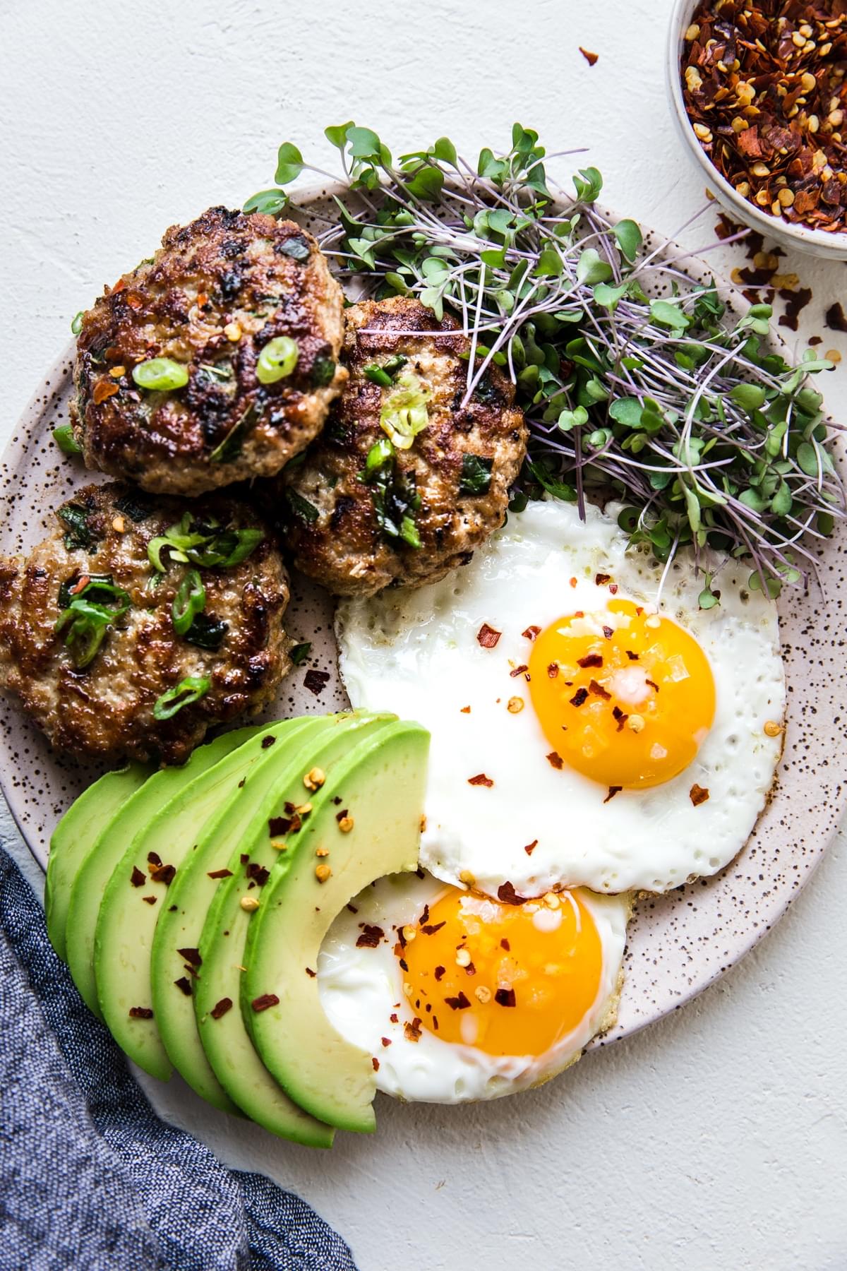 Asian flavored Breakfast Turkey Patties on a plate with eggs, avocados