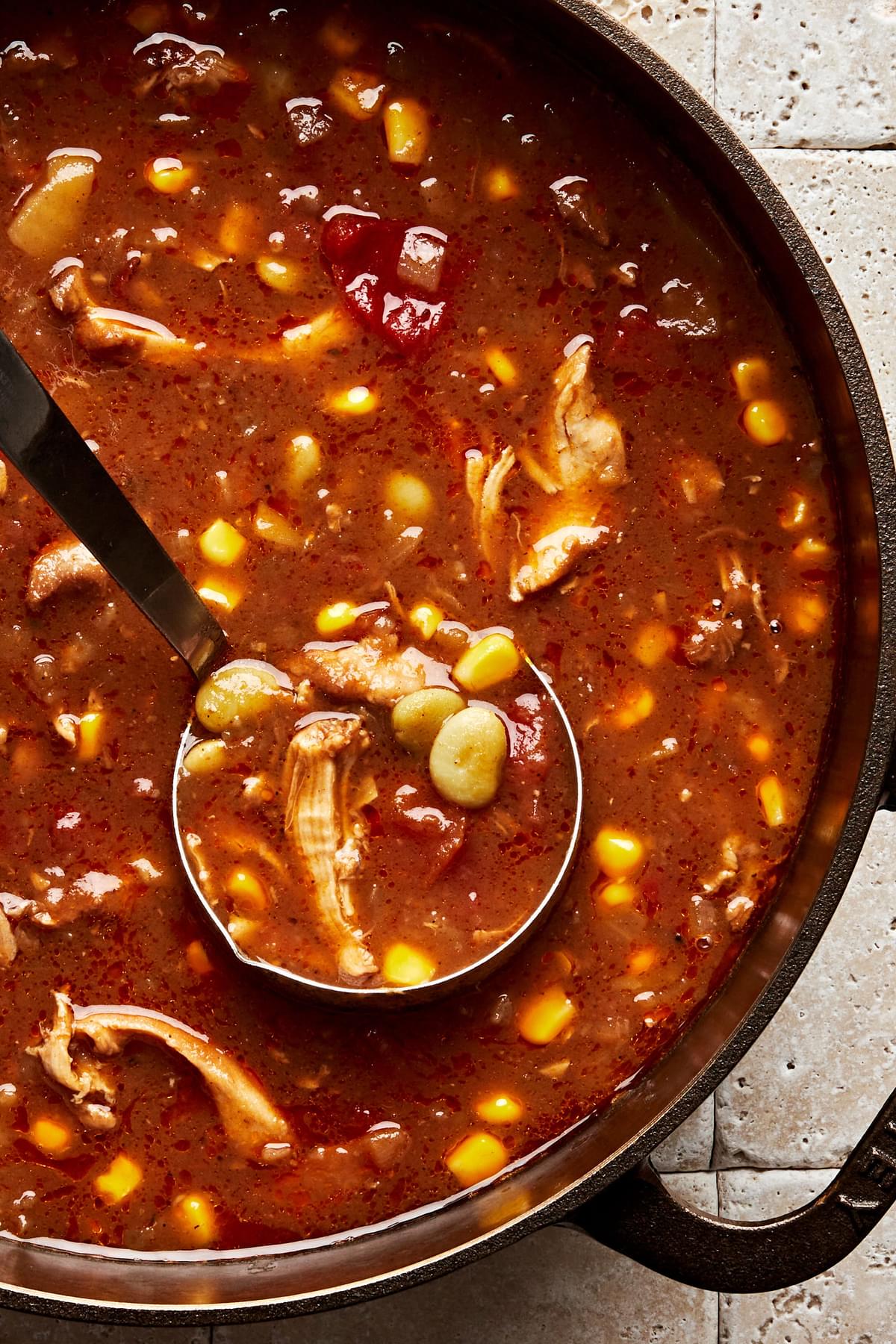 a pot of homemade Brunswick Stew with a ladle scooping a serving out