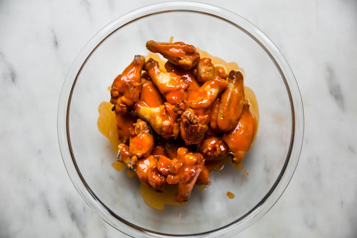 baked buffalo wings tossed in homemade buffalo sauce in a glass bowl on the counter