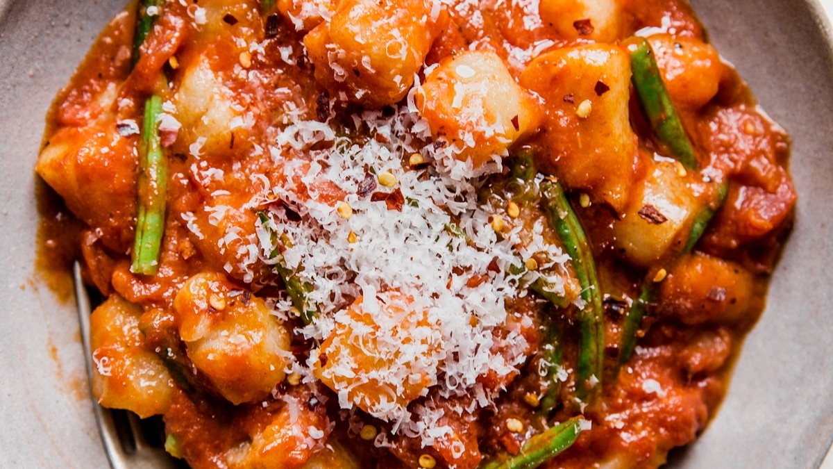 bowl of vodka sauce and green bean cauliflower gnocchi topped with parmesan cheese