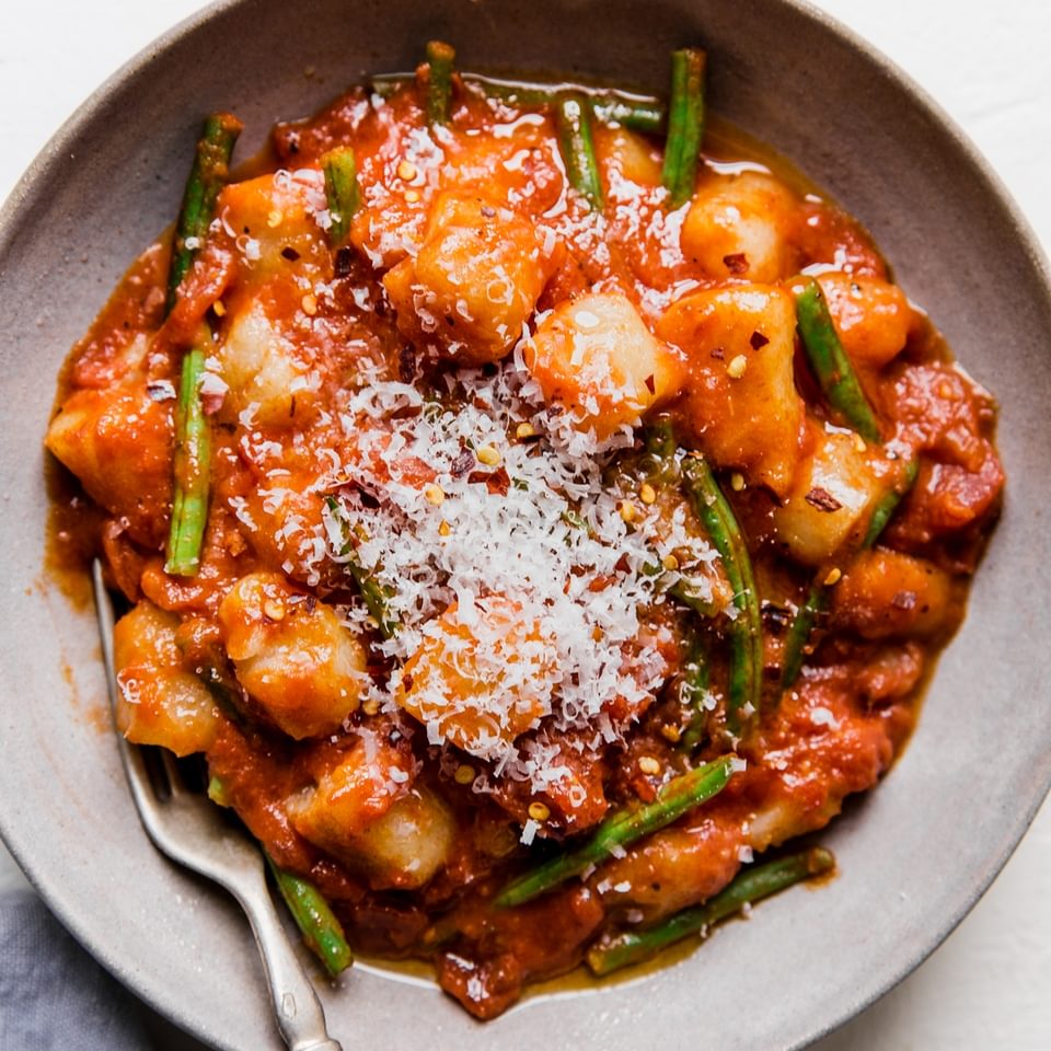 bowl of vodka sauce and green bean cauliflower gnocchi topped with parmesan cheese