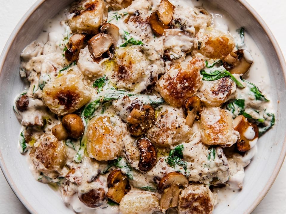 white bowl of mushroom alfredo cauliflower gnocchi