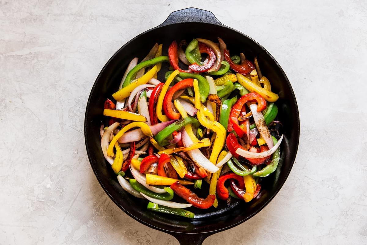 skillet of raw red, yellow and green bell peppers and onions