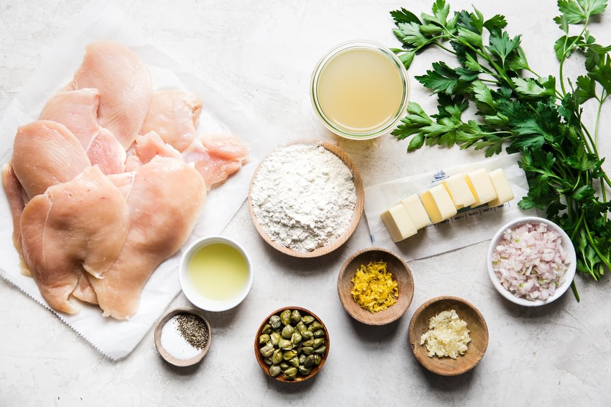 ingredients laid out for Chicken Piccata thinly cut chicken breast, flour, capers, lemon juice, olive oil, shallots