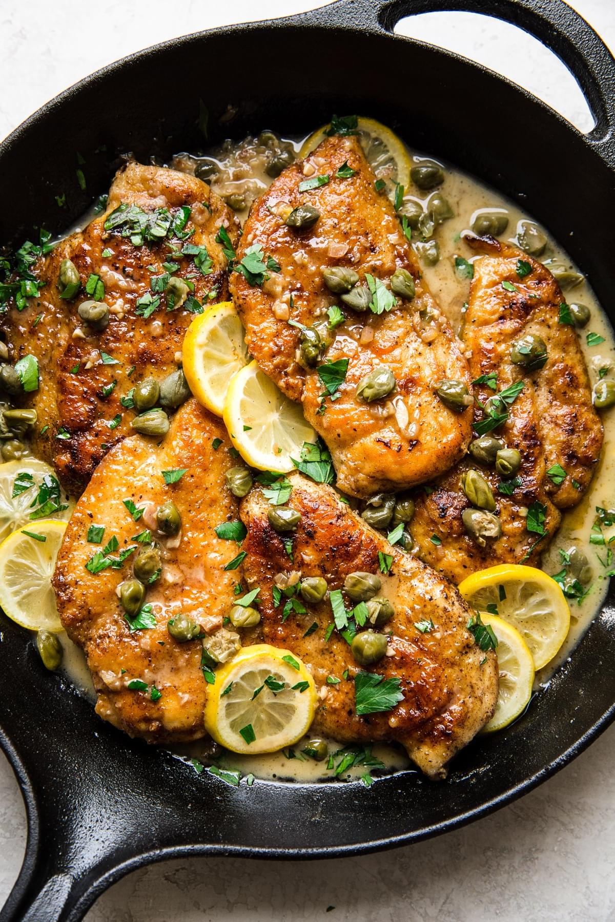 Chicken Piccatta in a skillet with lemon sauce and capers