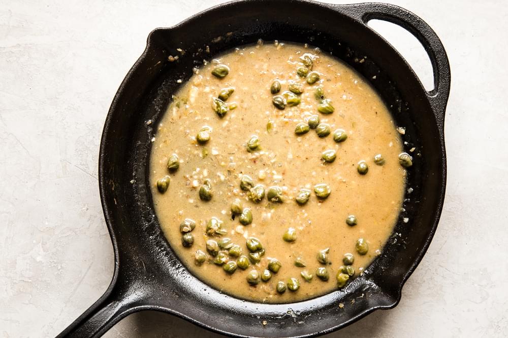Chicken Piccata sauce in a cast iron skillet with capers, butter and lemon