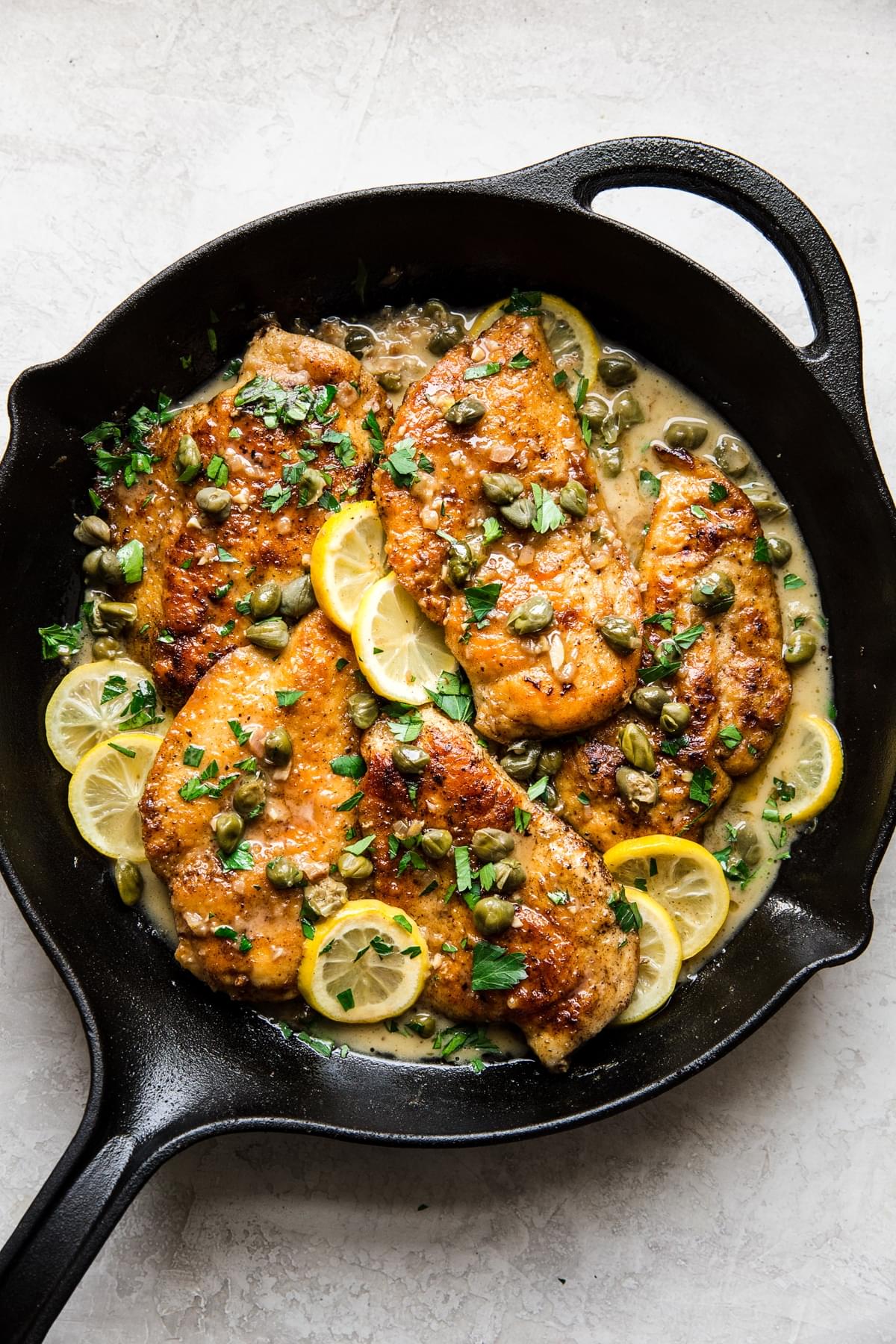 easy chicken piccata recipe with lemons and capers in a cast iron pan
