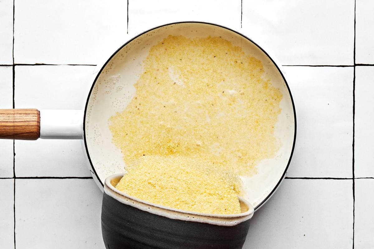 polenta being poured into a pot with milk and chicken stock