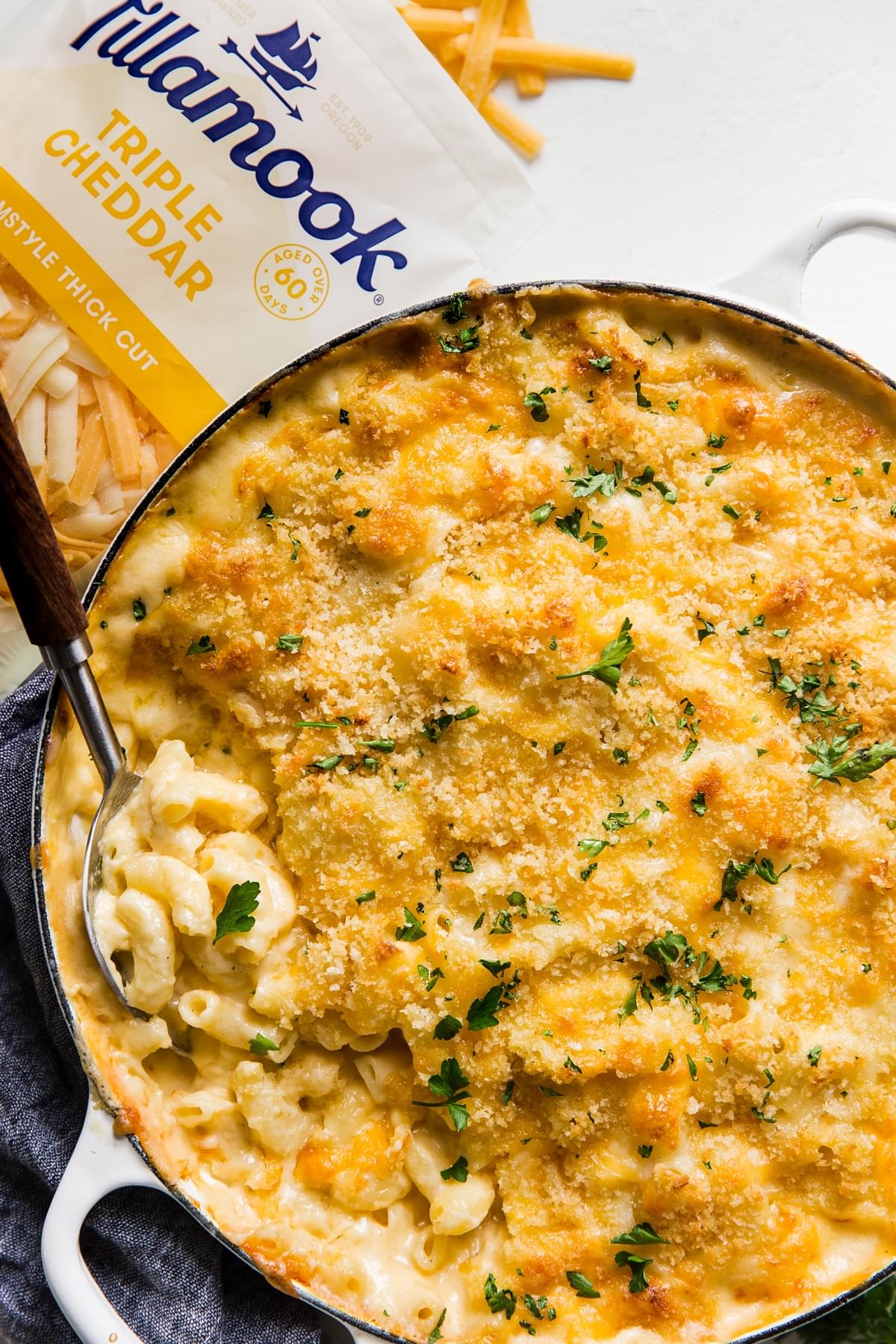 Classic Baked Macaroni And Cheese fresh from the oven with serving spoon and shredded Tillamook cheese in a bag