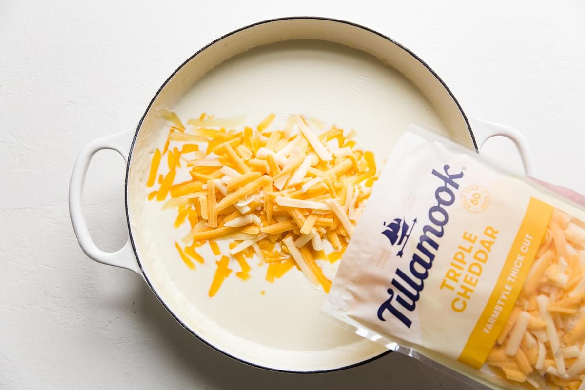 Tillamook cheddar cheese being added to milk and butter mixture.
