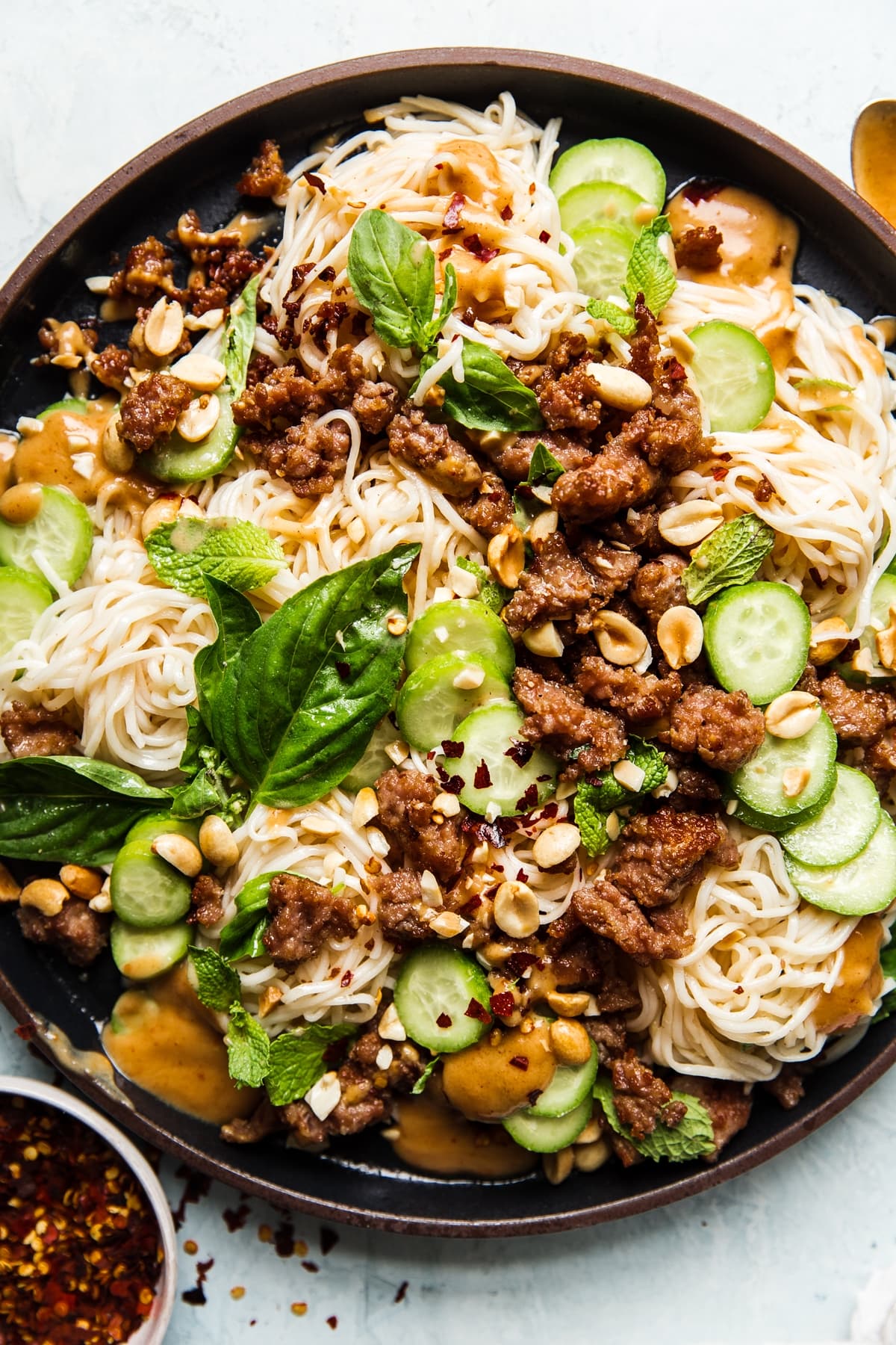 Cold Thai noodle salad topped with peanut dressing, crushed peanuts, ground pork, cucumbers, basil and mint