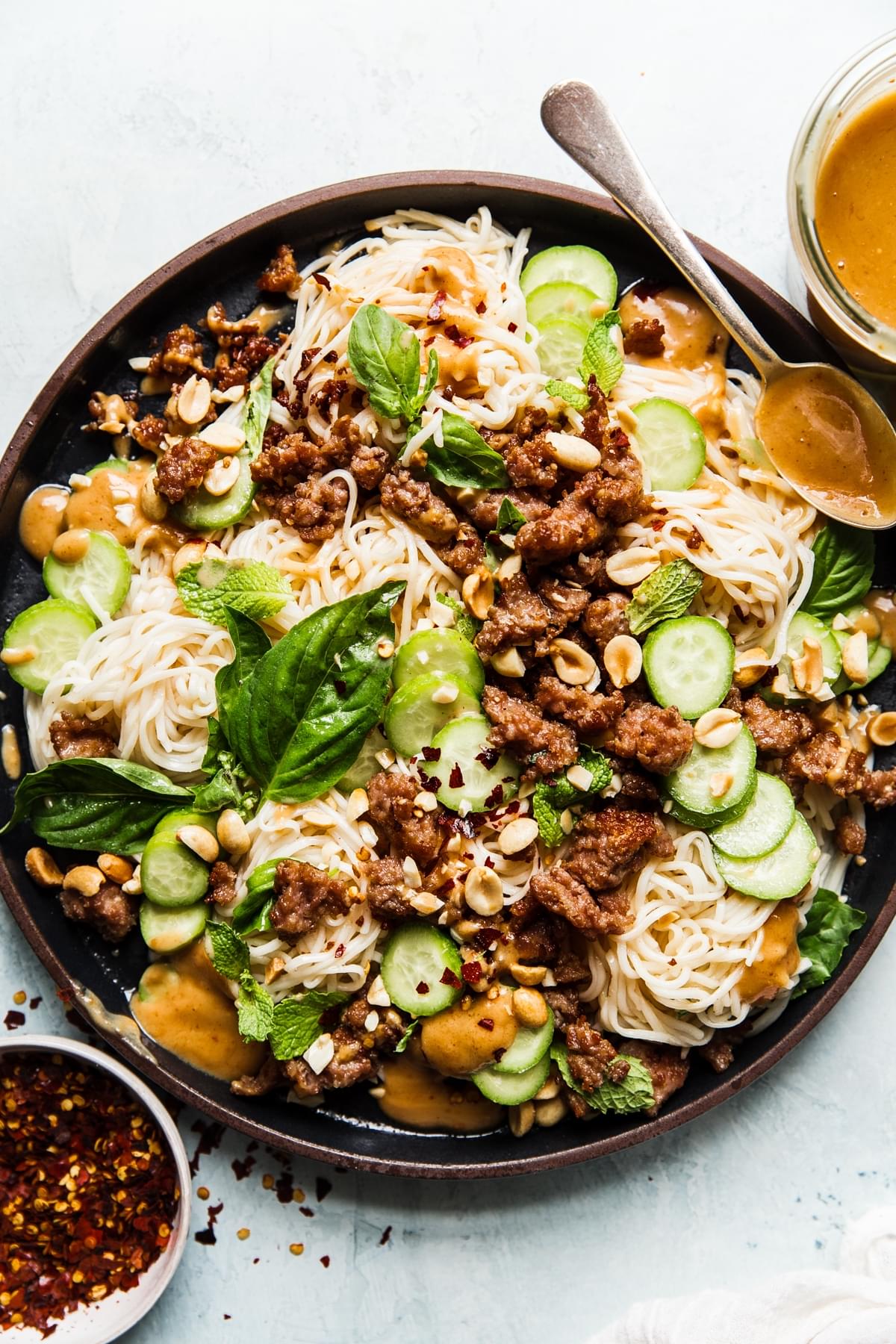 Cold Thai noodle salad topped with peanut dressing, crushed peanuts, ground pork, cucumbers, basil and mint