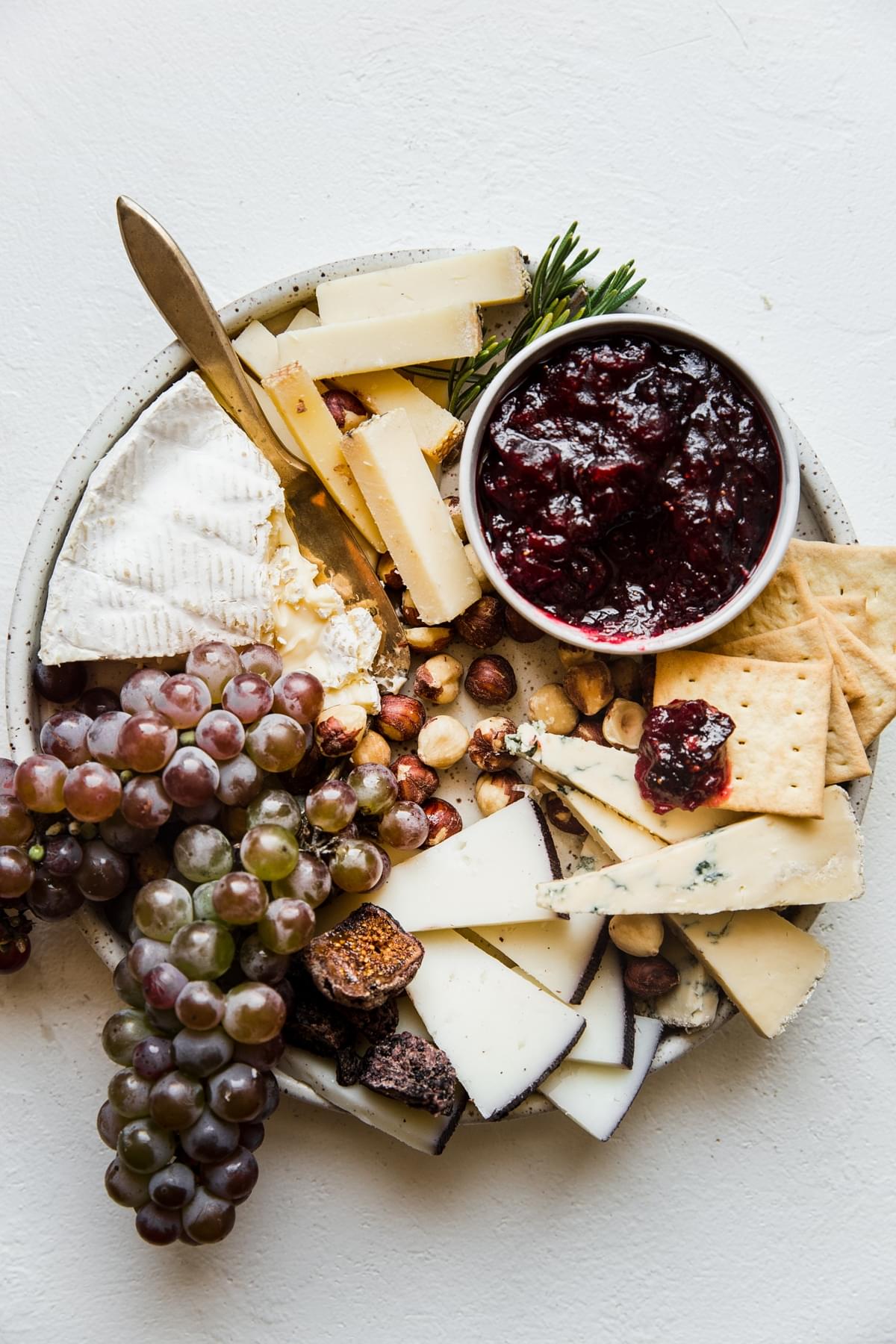 Cheese board with grapes, cheese, crackers and cranberry chutney