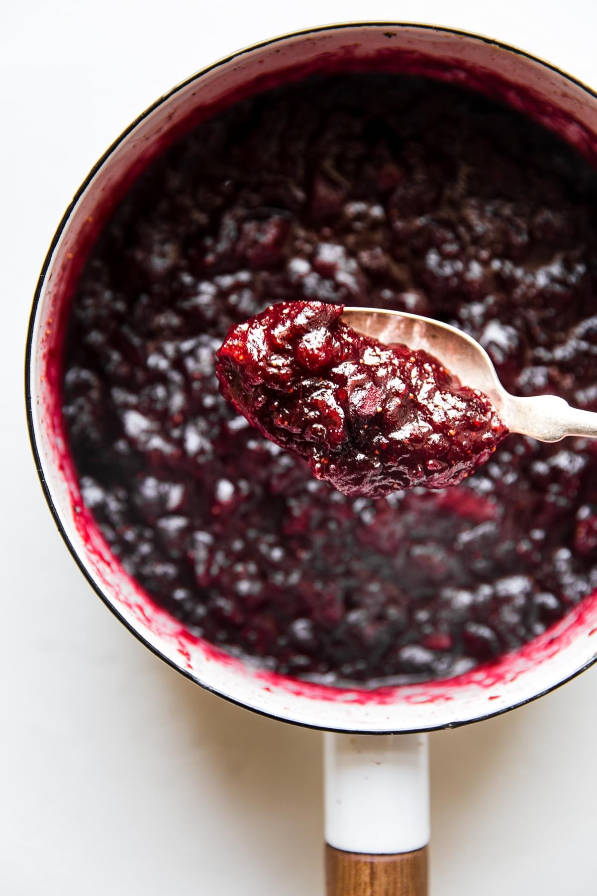 homemade cranberry chutney in a saucepan with a serving spoon