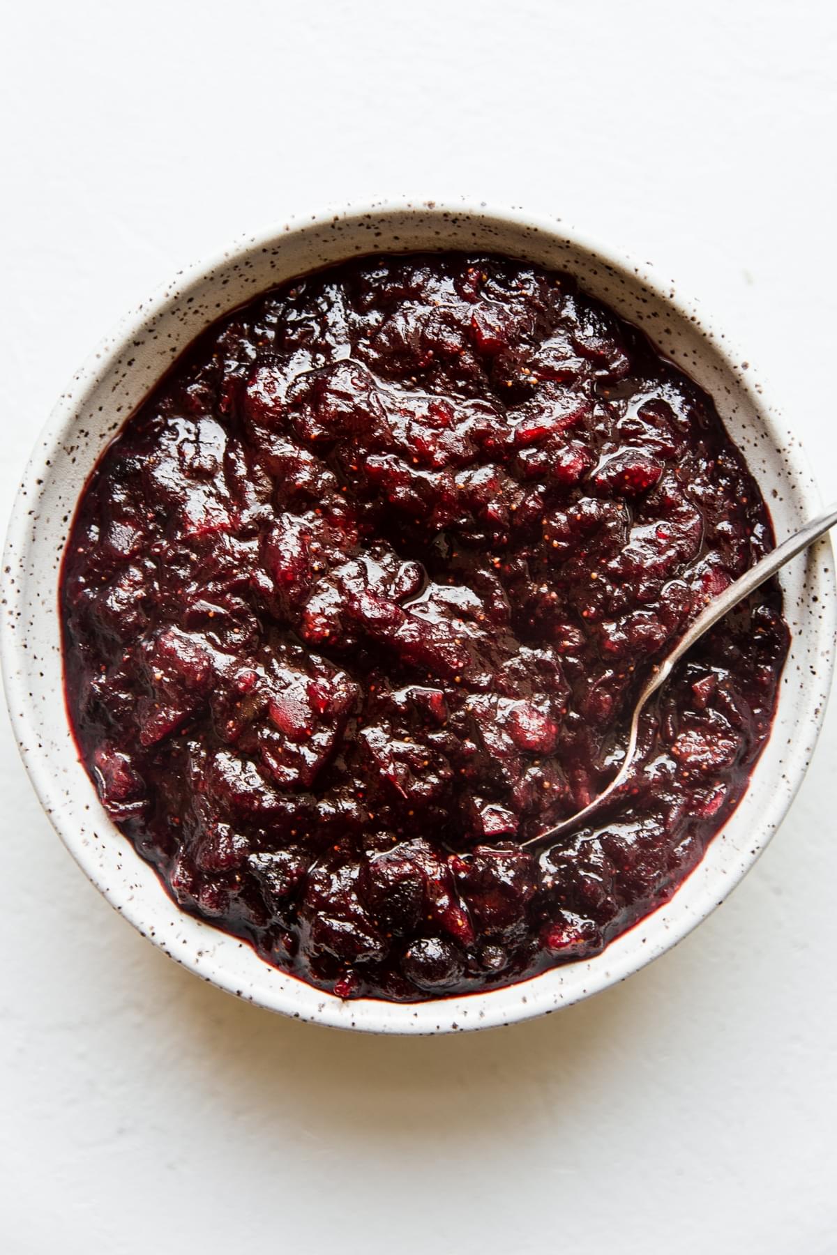 homemade cranberry chutney in a white bowl with a serving spoon