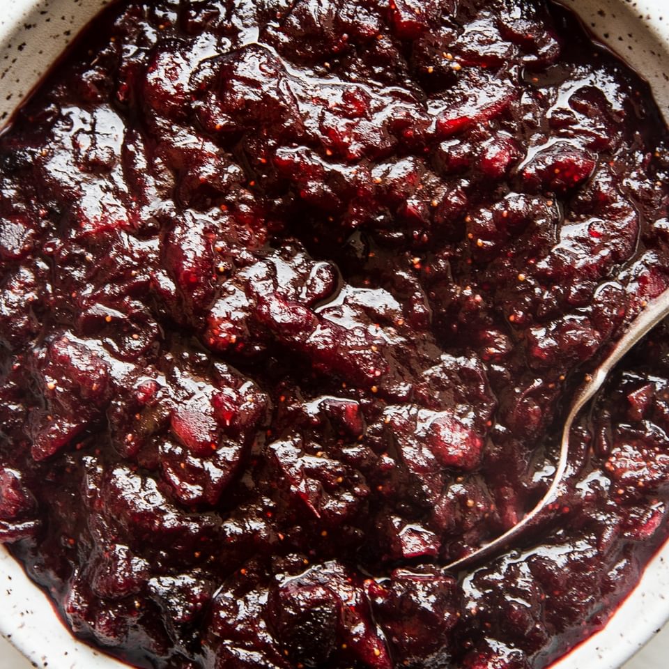 A bowl of cranberry chutney with a serving spoon