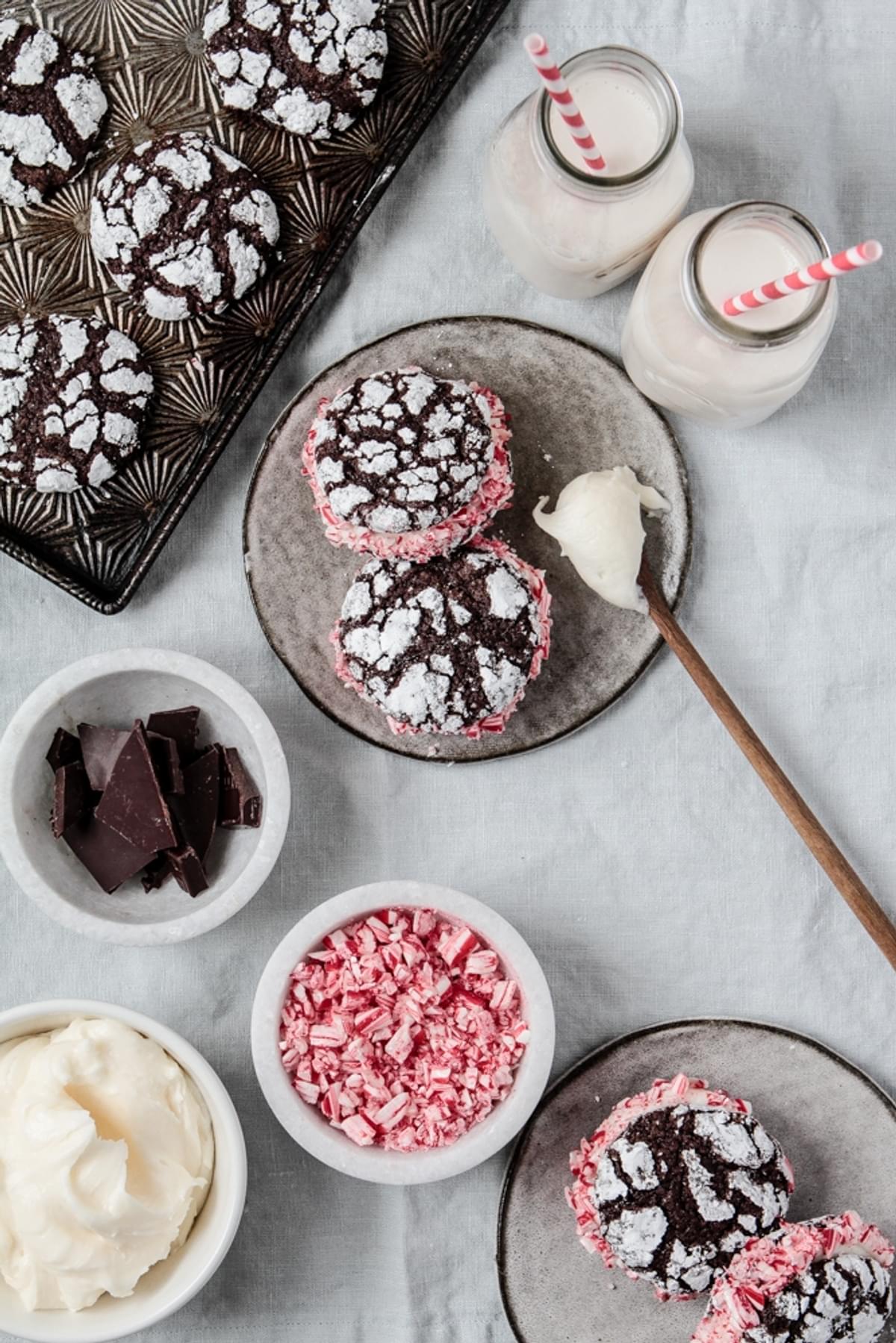Crinkle Cookies With Peppermint Cream on a plate with chocolate, frosting, and two glasses of milk