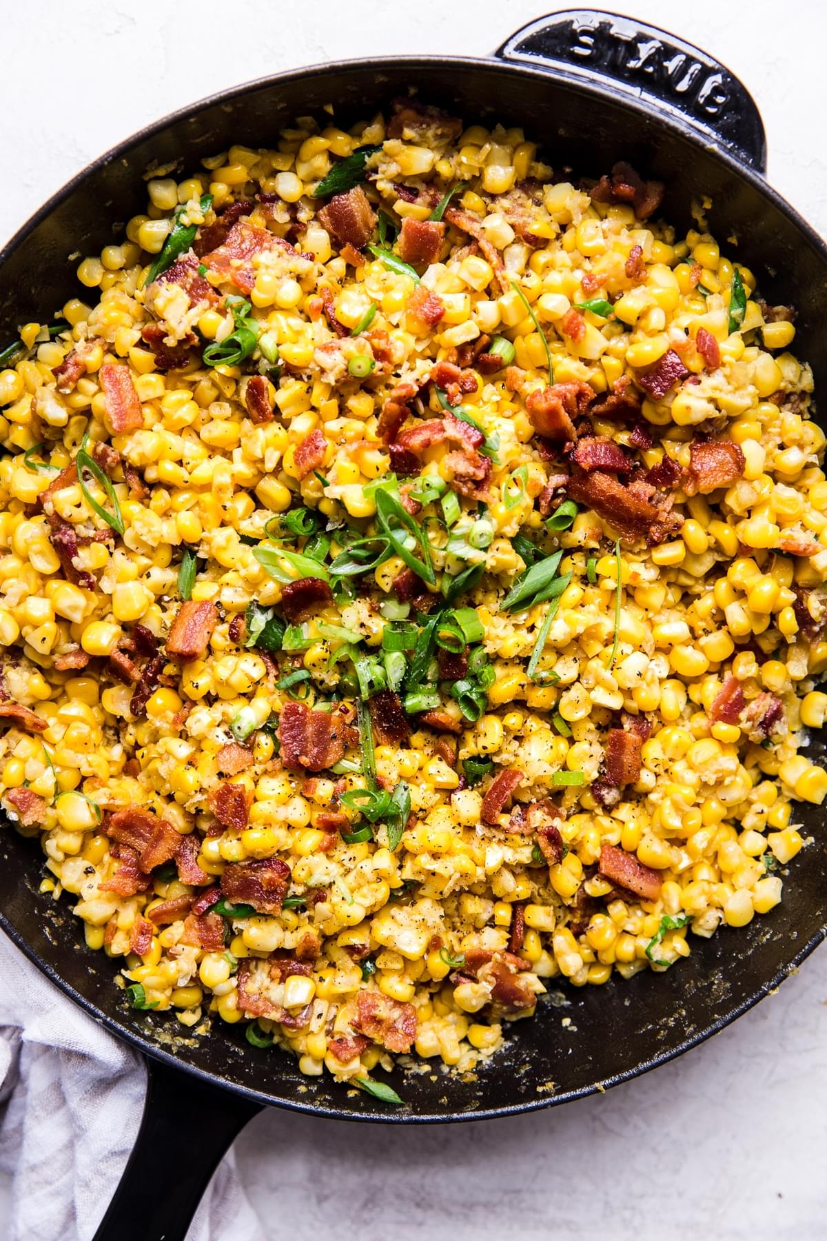 dairy free creamed corn in a skillet with bacon and green onions
