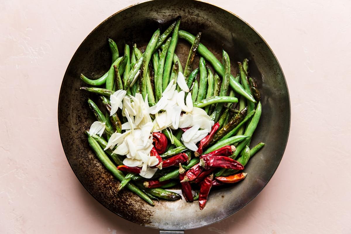 green beans, thinly sliced garlic cloves and dried red chillies in a skillet