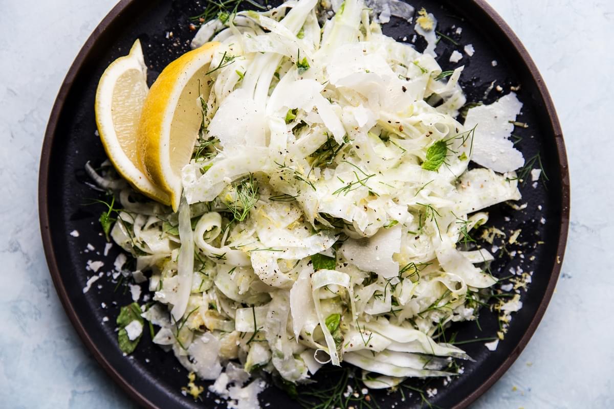 easy shaved fennel salad with lemon wedges on a plate