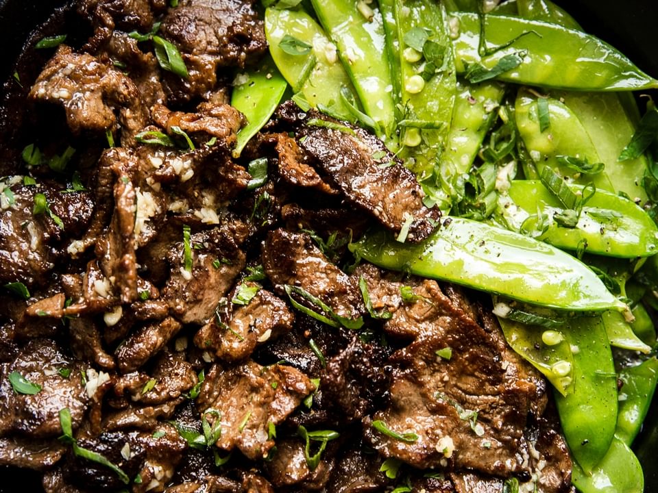 Garlic Butter Steak Stir-Fry with snappy peas in a cast iron pan