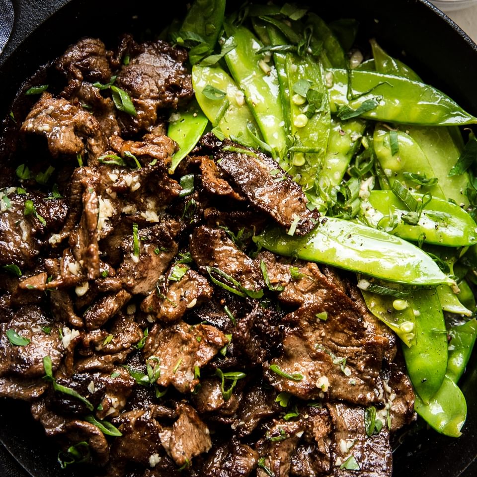Garlic Butter Steak Stir-Fry with snappy peas in a cast iron pan