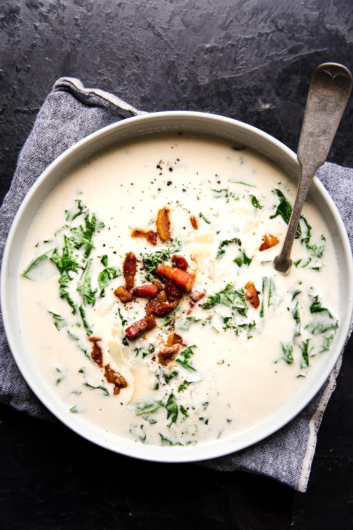 creamy garlic soup with kale and pancetta in a bowl