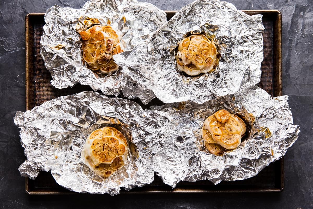 four roasted garlic heads on foil