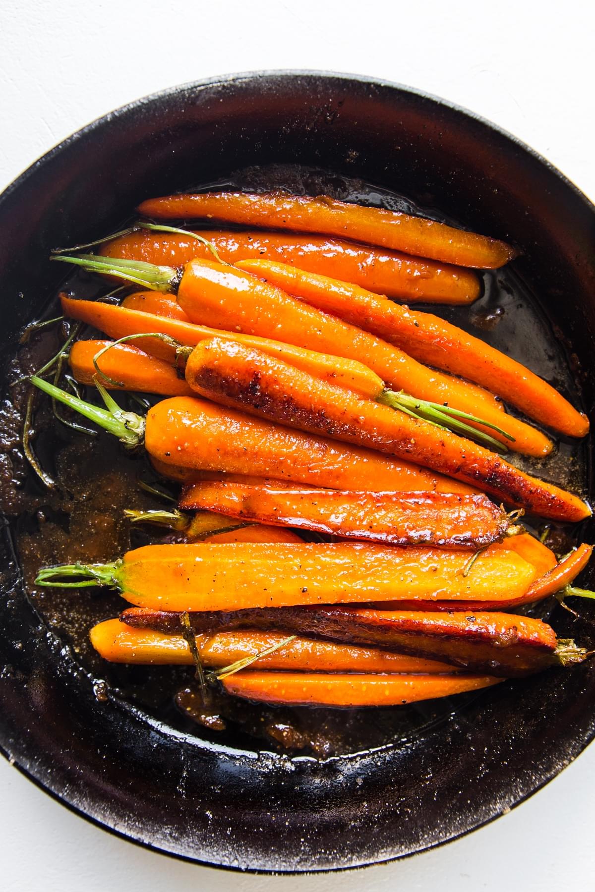 glazed orange carrots in a cast iron skillet