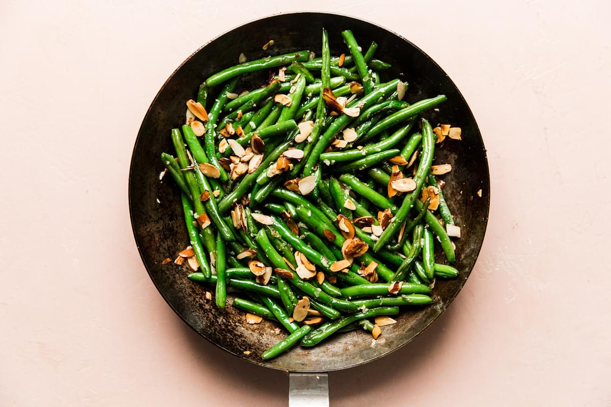 cooked green beans in a skillet with garlic and toasted almonds