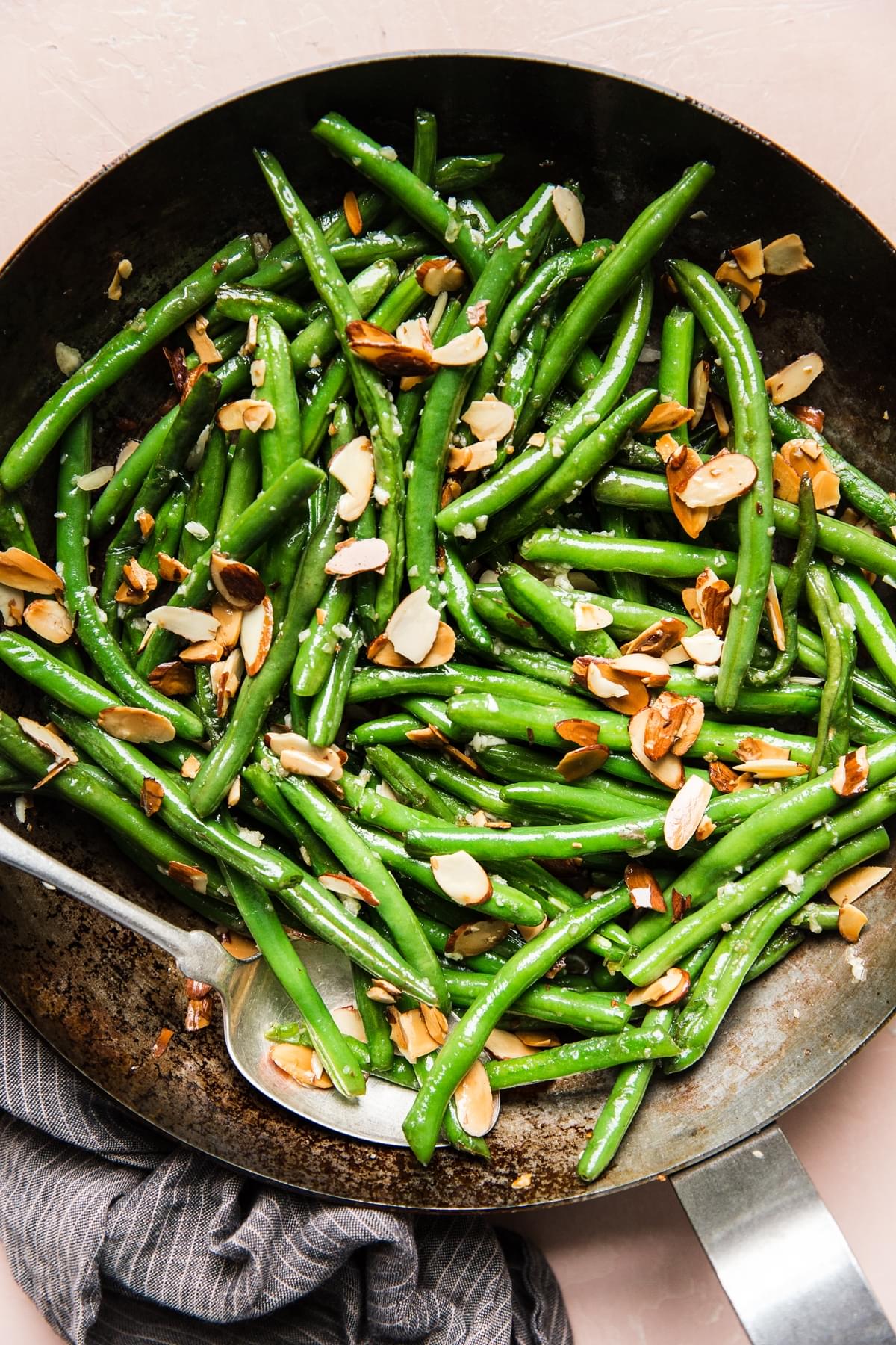 green bean almondine in a skillet with a serving spoon