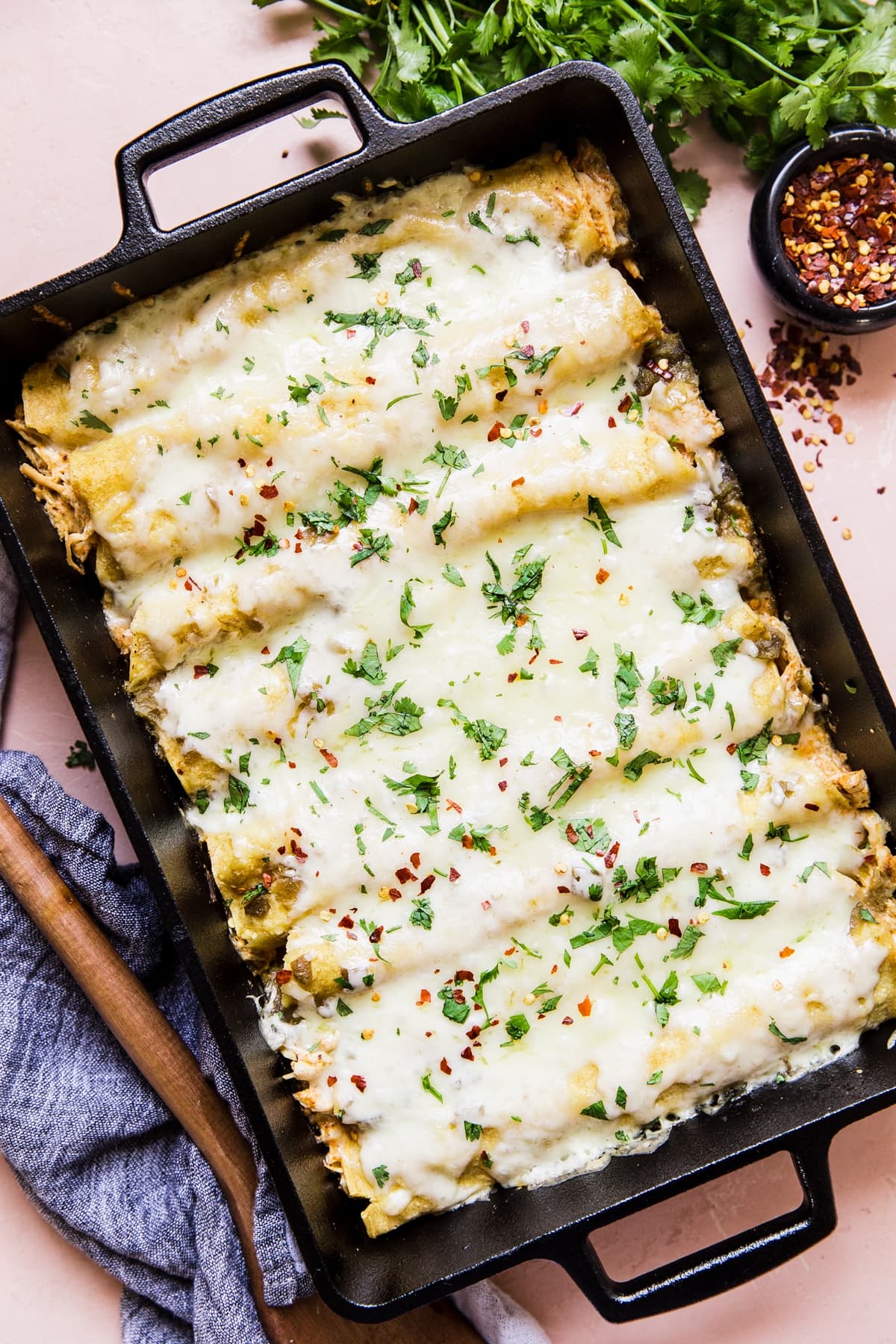 cheesy Green Chicken Enchiladas in a pan with serving spoon