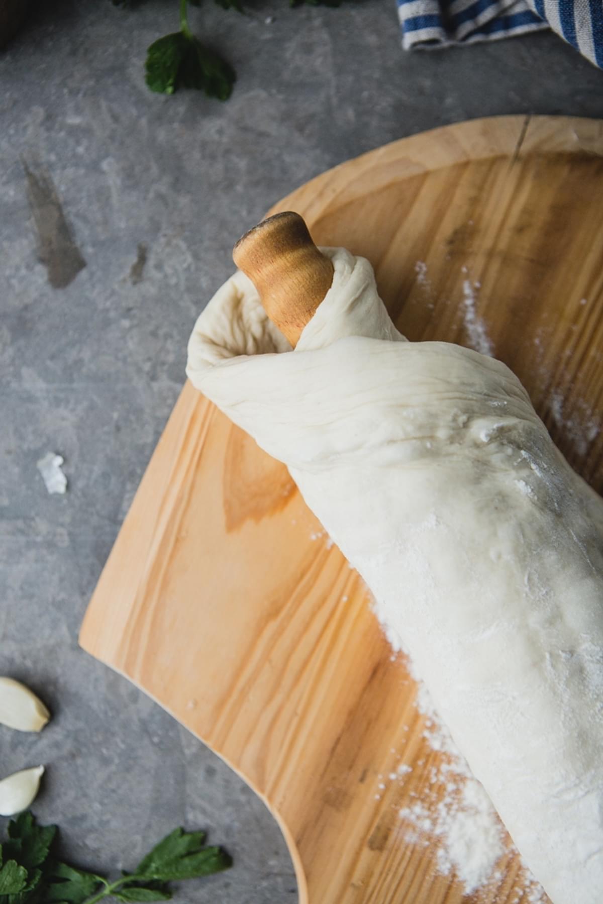 pizza dough rolled around a rolling pin topped with flour