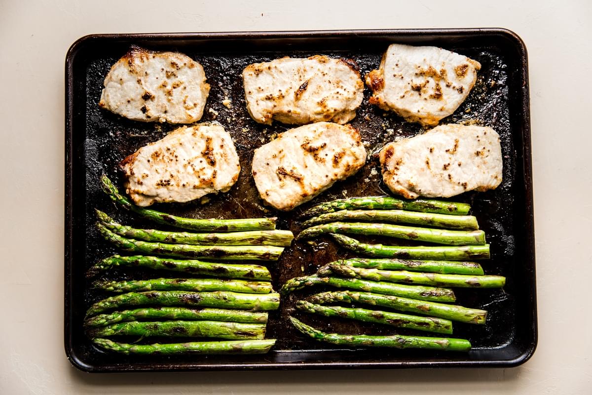 baked marinaded pork chops and asparagus on a sheet pan